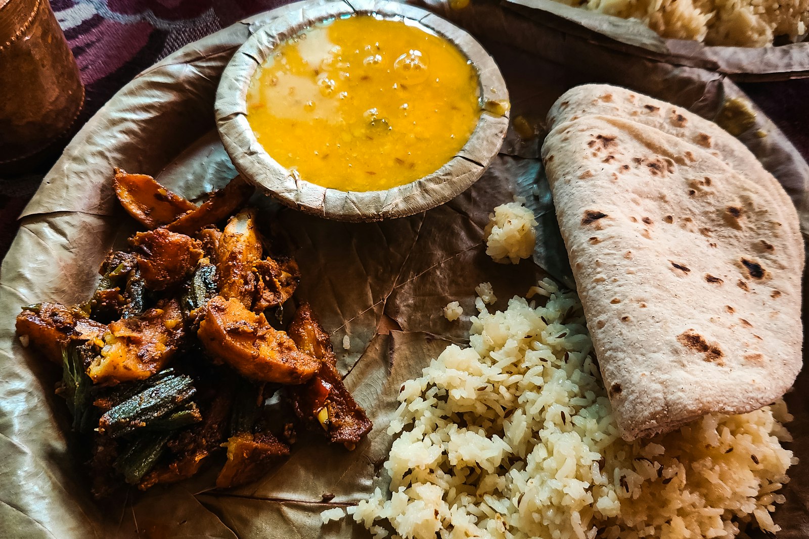 A traditional thali with dal, rice and roti served on a leaf plate